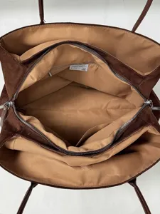 Interieurdetail van de bruine suède tote bag, met ruim hoofdvak en handige ritsvakken.