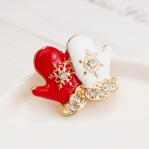 Close-up view of a Christmas mitten brooch, featuring red white enamel, rhinestones, and snowflakes.