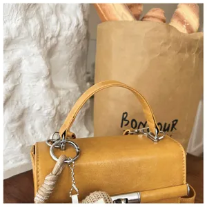 Detailed shot of a chic yellow mini top handle crossbody bag in a stylish lifestyle setting.