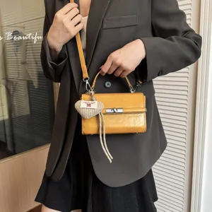 Yellow vintage crossbody handbag for women, top-handle small square bag with strap and cute heart pendant.