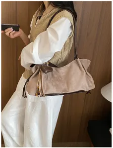 Detail view of a retro brown suede shoulder bag with cute heart tassel pendant accessory.