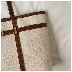 Canvas tote bag detail view, beige and brown leather contrast, elegant commuter handbag design.