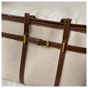Detail view of a vintage color-block canvas tote bag with brown leather straps and buckle.