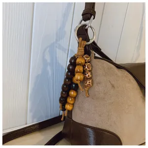 Retro brown shoulder bag detail featuring wooden bead charms, suede texture, and metal hardware.