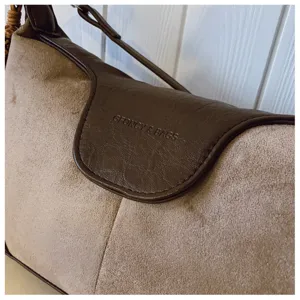 Close up view of vintage suede shoulder bag with brown leather flap and classic texture.