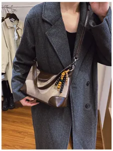 Retro canvas shoulder bag with brown leather trim and unique wooden bead charm detail.