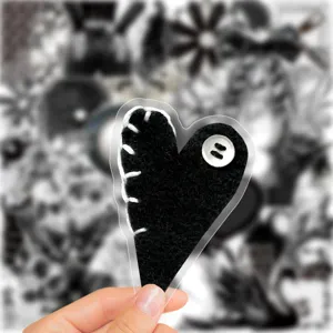 Adesivo a cuore in feltro nero con cuciture bianche e dettaglio bottone per album scrapbooking.