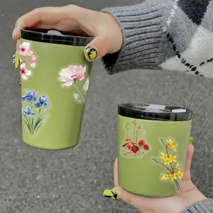 Detailed shot of green travel mugs decorated with vibrant watercolor floral stickers.