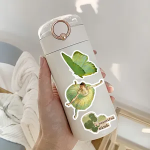 Detailaufnahme einer tragbaren Trinkflasche mit ästhetischen grünen Vintage-Aufklebern und Ring.