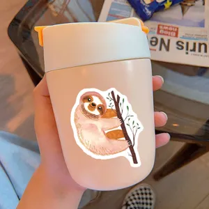 Close-up of a cute watercolor sloth sticker on a pink travel mug in a lifestyle scene.