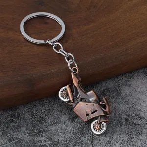 Close-up detail of vintage bronze motorcycle pendant on silver keyring keychain accessory.