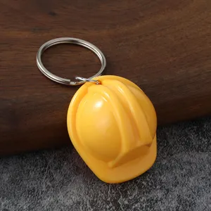 Vista de detalle en primer plano del llavero con casco de construcción amarillo y anillo metálico.