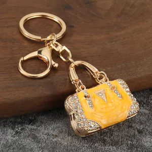 Gold-tone metal keychain featuring a chic yellow oil-drop handbag charm with sparkling rhinestones.