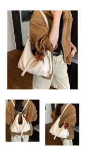 Detail view of the stylish white slouchy shoulder bag with cute plush bear pendant, versatile design.