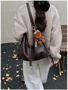 Close-up detail of retro brown shoulder tote bag with cute bear pendant, stylish lifestyle.