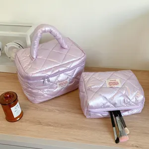 Detailed view of shiny quilted cosmetic bag with handle, portable makeup storage pouch.