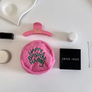 Detailed view of pink plush storage pouch and claw clip flat lay on white background aesthetic.