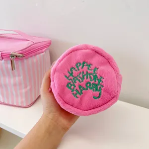 Detailed close-up view of cute pink plush round coin purse with green embroidery text.