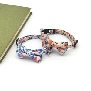 Close-up detail of cute floral cat collars featuring sweet bowties and metal bells for pets.