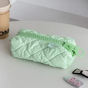 Green quilted cosmetic bag with large zipper detail, minimalist travel pouch