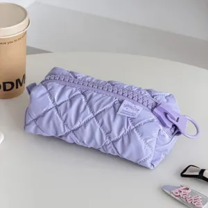 Detailed view of a pastel purple quilted cosmetic bag featuring glossy fabric and an oversized zipper.