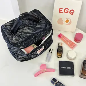 Detailed view of black quilted down cosmetic bag with portable handle and makeup storage props.