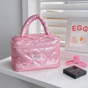 Detail view of the pink quilted shiny cosmetic bag, showing fabric texture and practical handle.