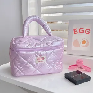 Puffer cosmetic bag detail showing glossy quilted texture, zipper and top handle.