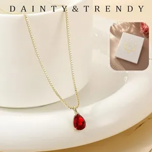 Close-up of a delicate gold-plated box chain necklace with a red teardrop zircon pendant.