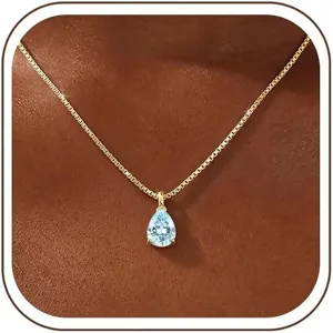 Close-up detail of a stunning pear-shaped light blue gemstone pendant on a gold box chain.