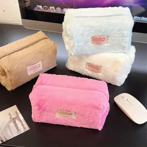 Detail shot of plush cosmetic bags in multiple colors with cute woven labels for daily storage.