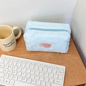 Close-up detail shot of a soft blue plush makeup bag showcasing its fluffy texture and zipper.
