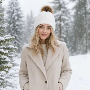 Close-up detail of a stylish white winter knit beanie with fluffy pom pom for women.