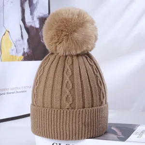 Close-up detail of winter cable-knit beanie with fluffy pom-pom, soft warm textured hat.
