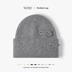 Detail shot of grey knitted cap with dual bows, soft rabbit hair blend fabric for autumn.