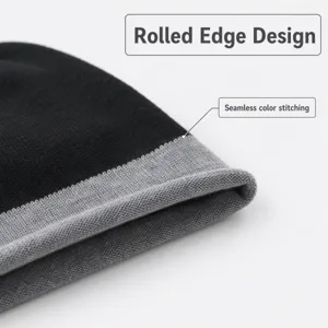 Black and grey knit beanie detail shot, rolled edge design, seamless color stitching.