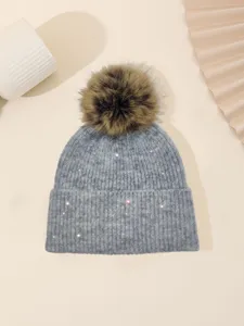 Grey knit beanie with fluffy brown pom-pom and sparkle sequins for winter warmth.