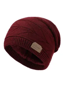 Close-up view of the wine red knitted beanie showing soft plush fleece lining and brand patch.