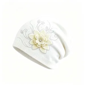 Detailed view of white knitted beanie featuring 3D fabric flower and rhinestone details.