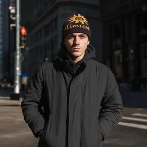 Close-up detail of the vintage knit beanie with Optimism letter and sunflower jacquard pattern.