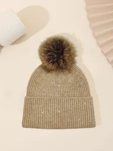 Detail view of a cozy knit beanie with sparkly sequins and fluffy pom-pom for winter warmth.