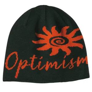 Close-up detail showing the knitted sun flower graphic and Optimism lettering on the winter beanie.