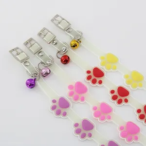 Glowing pet collar detail view featuring cute colorful paw print designs and metal bells.