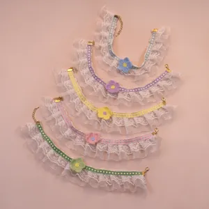 Close-up of cute pet lace ruffles collar with colorful knitted flower and checked ribbon.