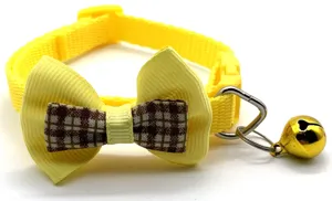 Close up of yellow pet collar with cute plaid bow and gold bell, detail shot of cat accessory.