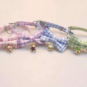 Detailed view of cute plaid pet collars with bows and floral bells, perfect for cats and dogs.