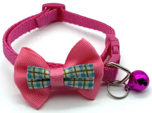 Close-up of pink pet collar detail, featuring bowknot decor, plastic buckle and metal bell.