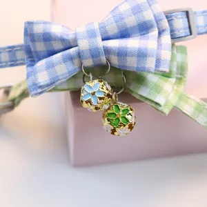 Close-up detail of cute pet collar featuring double-layer plaid bows and floral enamel bells.
