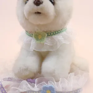 Detailed close-up of delicate white lace pet collar with green flower decoration on plush toy.
