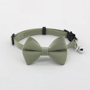 Close-up detail of light green pet cat collar with cute bow tie and metallic bell attachment.